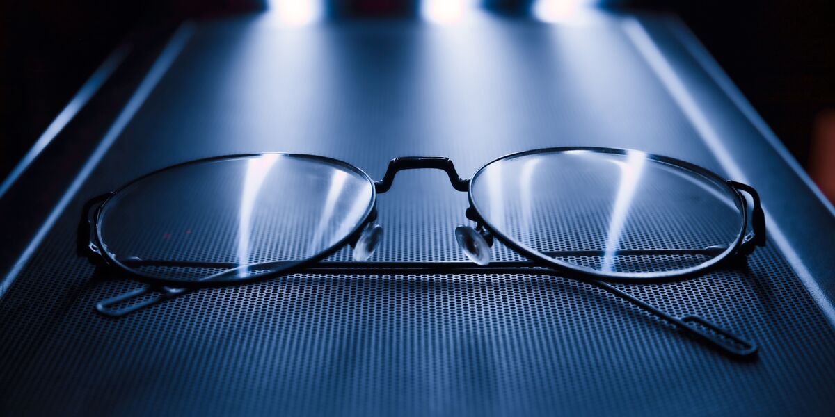 Metal glasses on a dark surface with light reflecting across the lenses