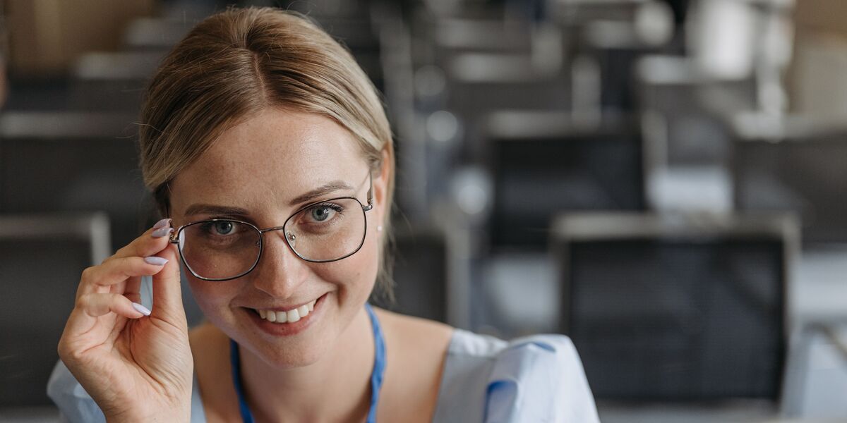 Woman facing the camera and holding the side of her glasses